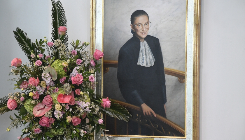 Flowers in front of a portrait of Ruth Bader Ginsburg.