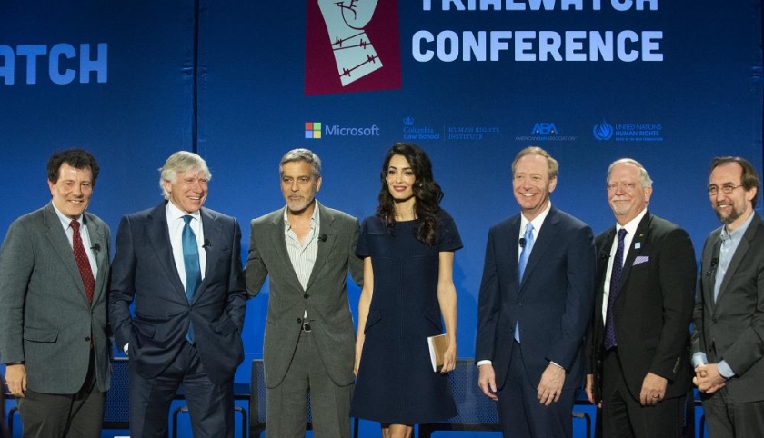 6 men in suits flank a woman in black dress