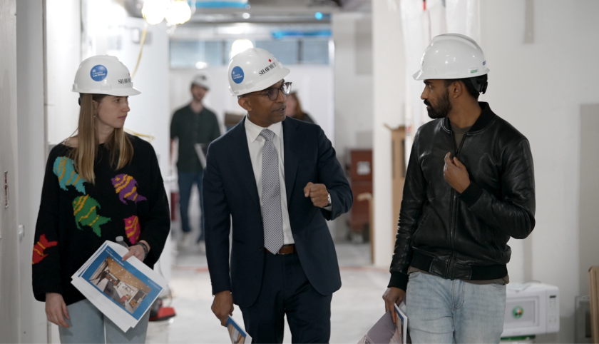 Two. men and a woman in hardhats walking and talking