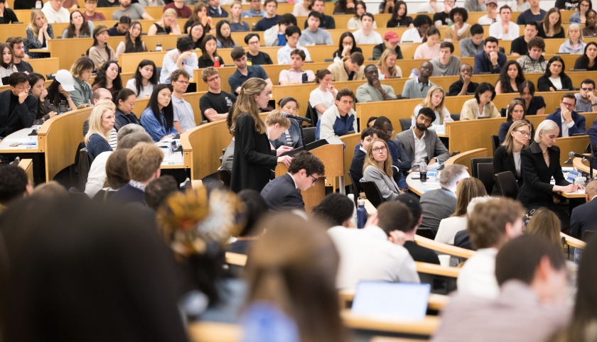 A student at the podium surrounded by fellow students, faculty, and family watching the 2026 Harlan Fiske Stone Moot Court finals.