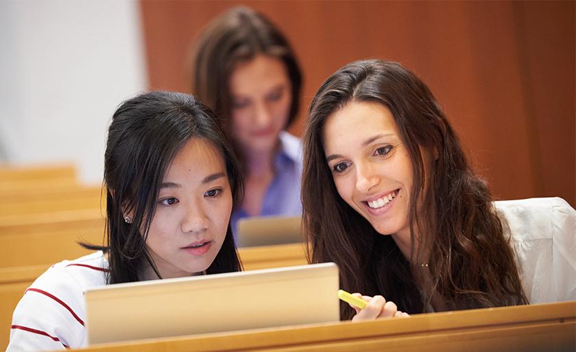 Two students look at a laptop in class.