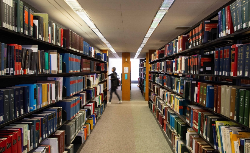 A student walks past a shelf of books in the Diamond Law Library