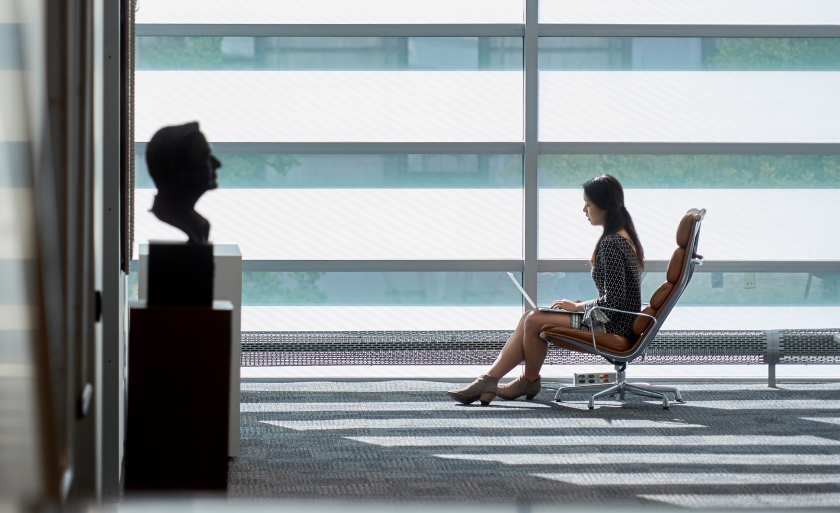 A student sits in Jerome Greene Hall with her laptop.