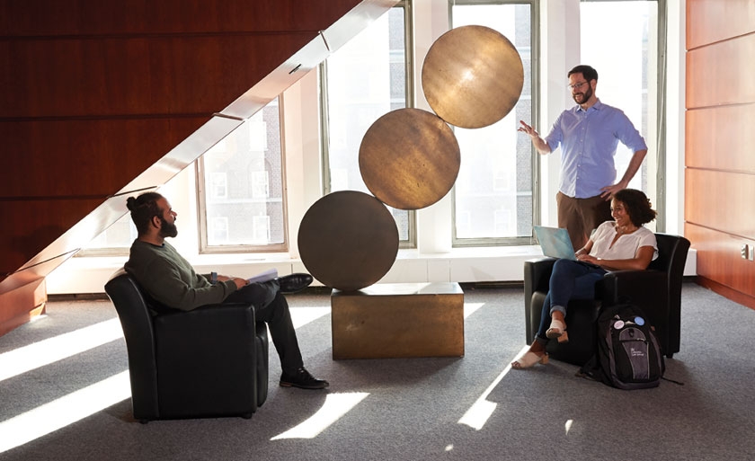 Students in Jerome Greene Hall with circular sculpture