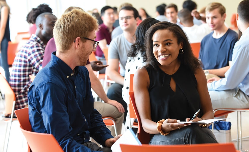 Students at orientation in orange chairs