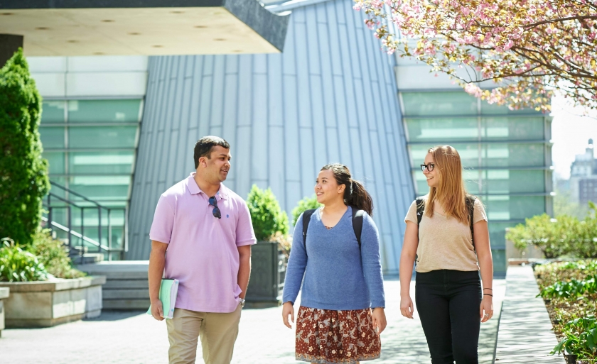 Students talking outside on Revson Plaza walking under cherry tree