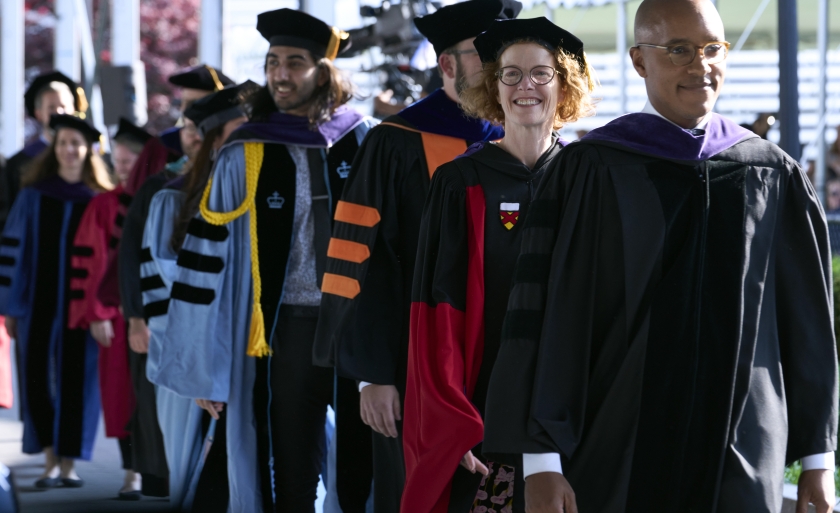 A line of faculty and students in academic regalia walking