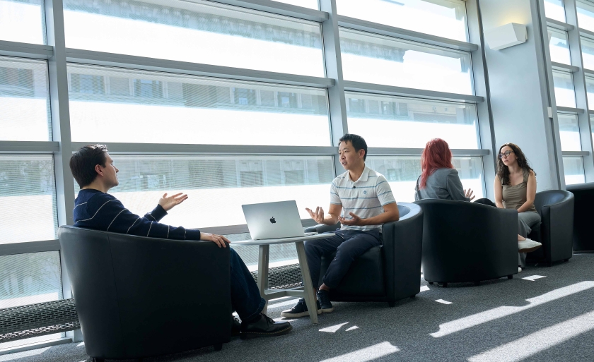 Students sitting in lounge chairs with laptops in Jerome Greene Hall.