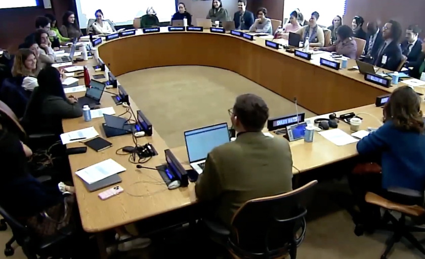 A group of people sit around a semi-circular table at the United Nations.