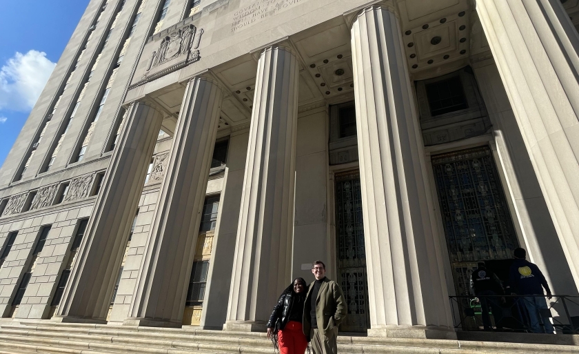 Two people stand in front of the portico of the Bronx Civil Court building.