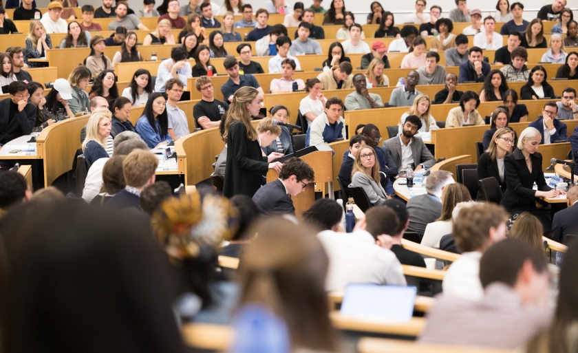 A student at the podium surrounded by fellow students, faculty, and family watching the 2026 Harlan Fiske Stone Moot Court finals.