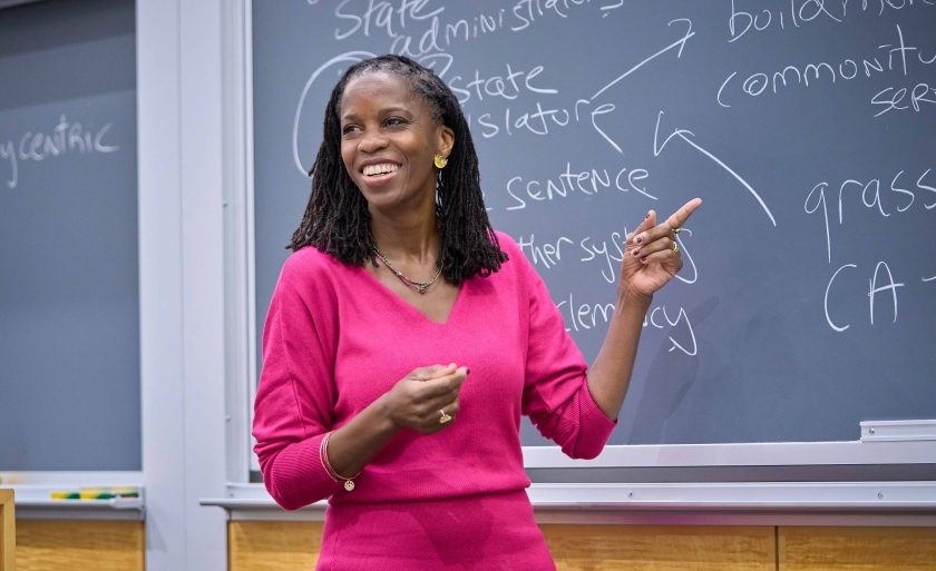 Professor Olatunde Johnson smiling while teaching in front of a blackboard.