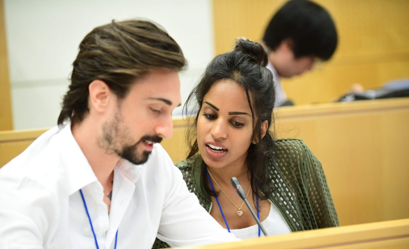 Two students study in a lecture hall with microphones in front of them.