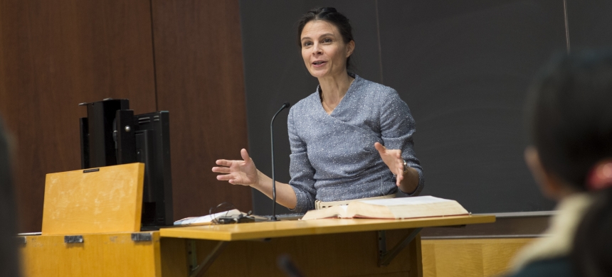 Professor Maeve Glass stands behind a lectern in a classroom at Columbia Law School/