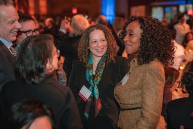 Three women talking at crowded event 