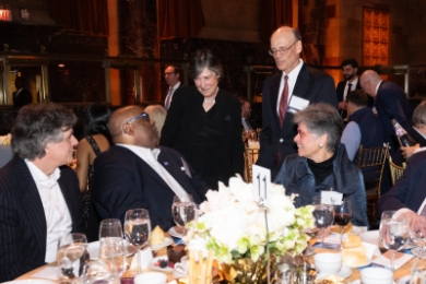 Elizabeth Glazer ’86 and judge talking to people seated at table