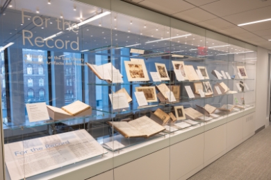 Glass case filled with books and a sign that says "For the Record"