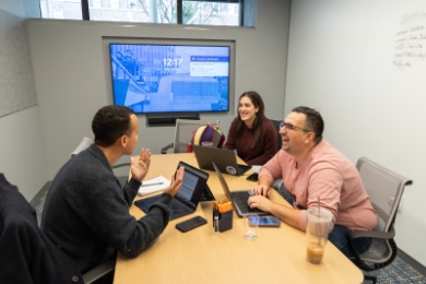 Students sitting at a table in front of a monitor