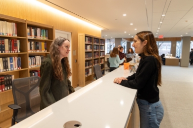Two women talking on either side of a counter