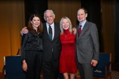 George Bermann with his arms around his wife Sandra Bermann and friend Amy Gutmann in red dress next to her husband Michael Doyle in suit and tie
