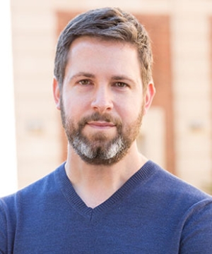 Portrait of Professor David Pozen, who is standing in front of a brick wall and smiling.