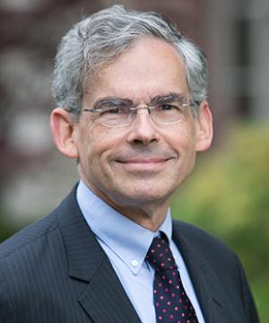 Michael Gerrard smiling in front of some shrubs outside the law school