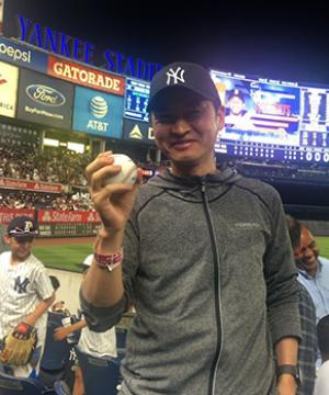 An Executive LL.M. student holds a fly ball he caught in front of the score board at Yankee Stadium.