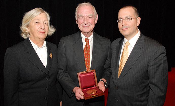 Gerry Lenfest, standing between Marguerite Lenfest and Columbia Law School Dean David Schizer, holds the Medal of Excellence in a box lined with red satin.
