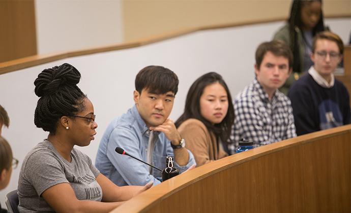 A student in a lecture hall speaks into her microphone.