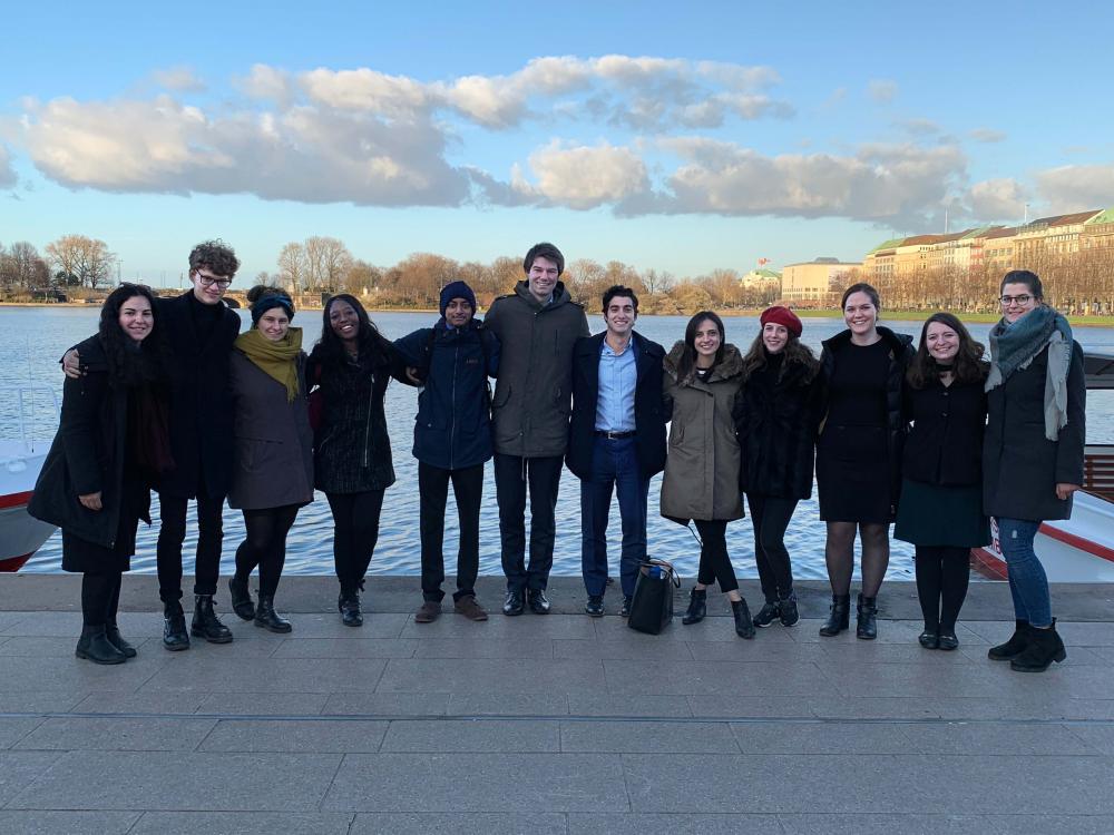 Students pose in front of an inland body of water.
