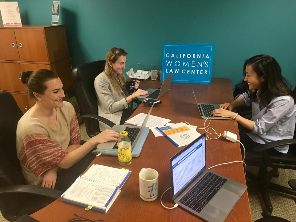 Three students from the Columbia Law Women's Association do legal work on laptops.