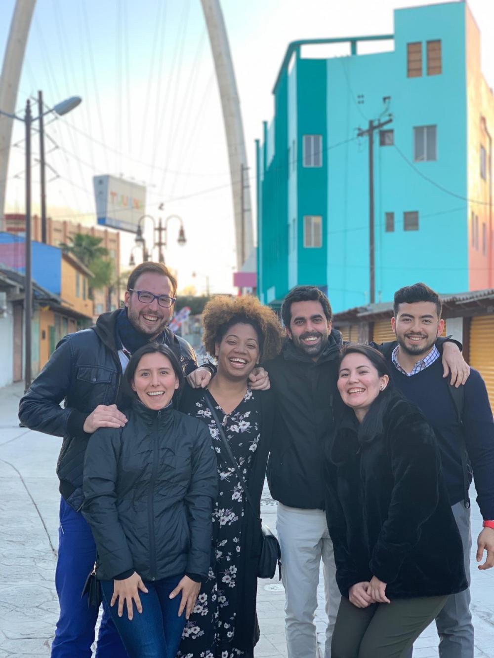Six students pose in front of a teal building in Tijuana.
