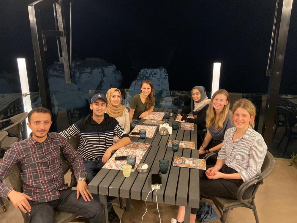 Six people sit around a table, smiling.