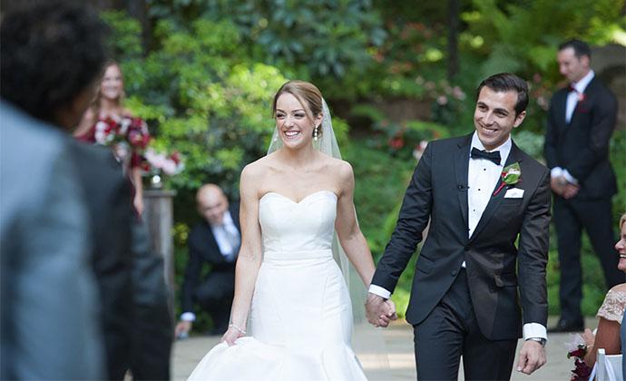 Grace and Ramsey hold hands walking down the aisle at their wedding.