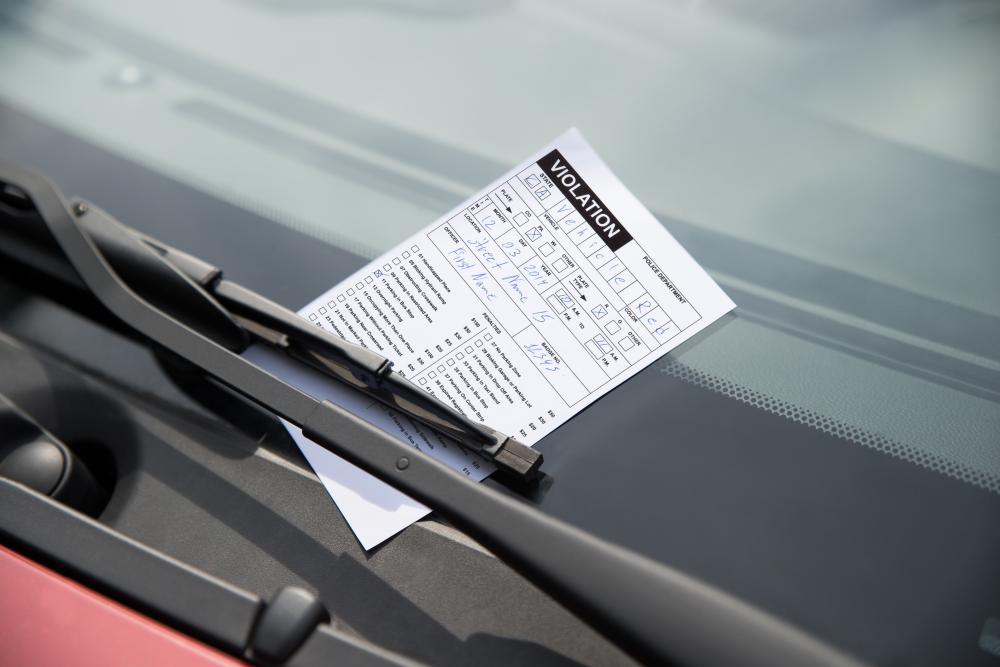A parking ticket tucked under the windshield wiper of a car