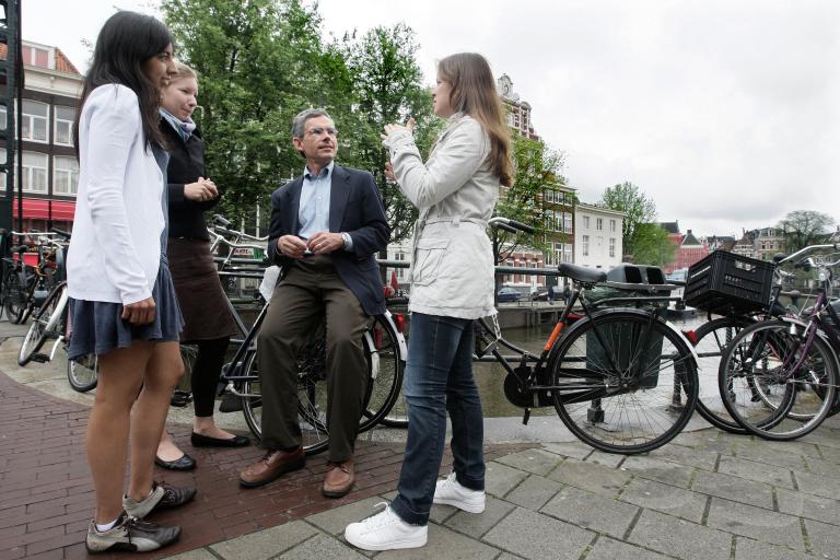 Students stand by a canal in Amsterdam.