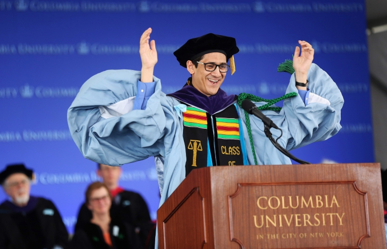 Andres Barajas ’17, J.D. class speaker, raises his arms and smiles at the 2017 Graduation ceremony.