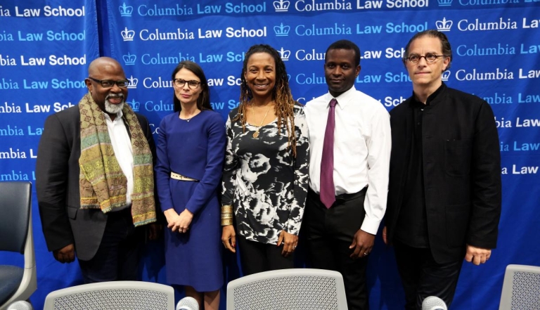 Five Columbia Law professors standing in front of a blue backdrop with the words Columbia Law School repeated many times