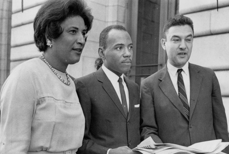 A woman and two men outside a court building. 