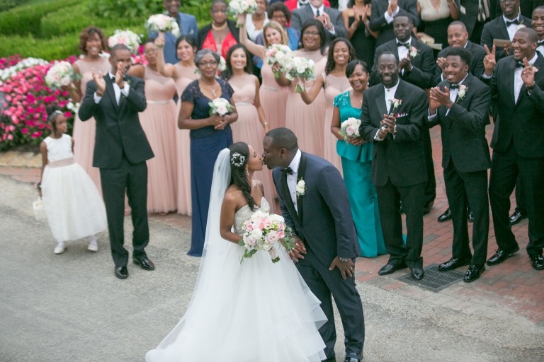 Samara Penn Savary ’10 and Mikhaile Savary ’09 kissing at their wedding in 2016 with guests looking on.