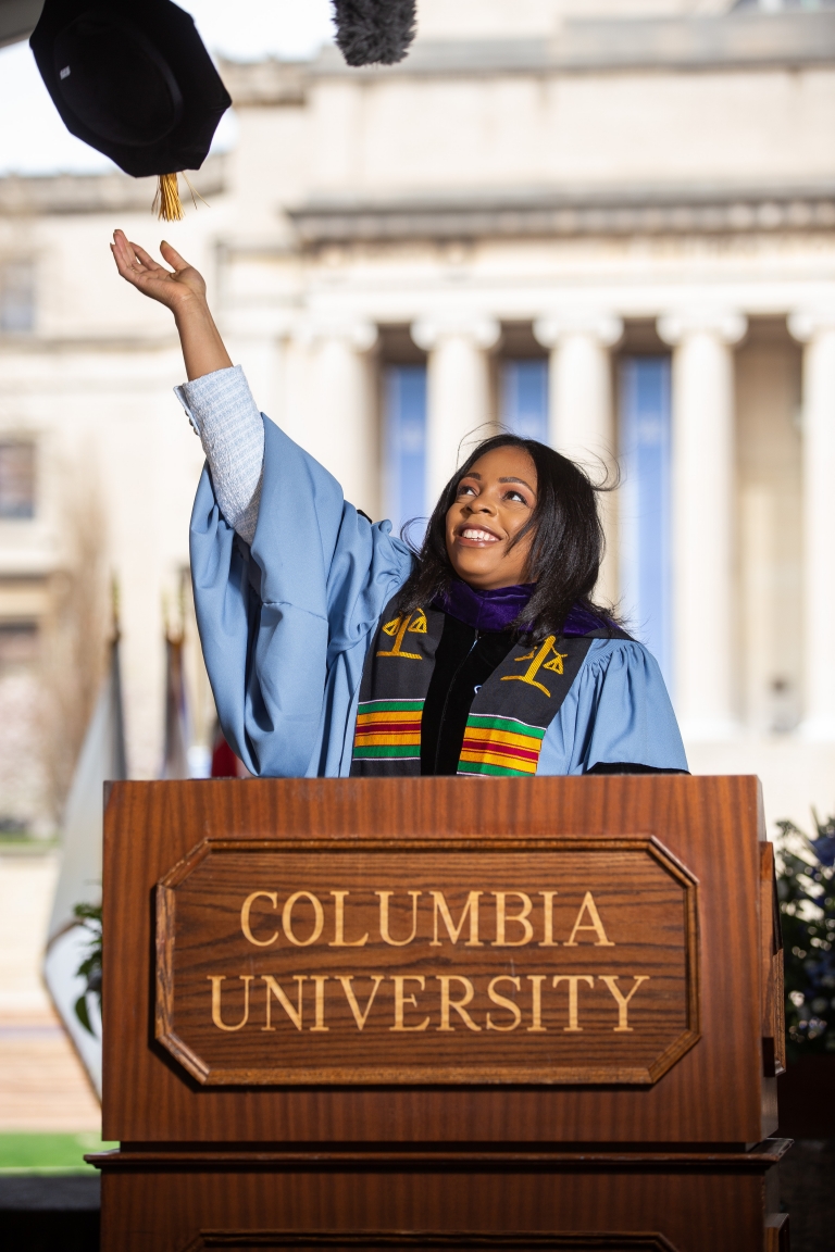 Woman in academic robes tossing her hat