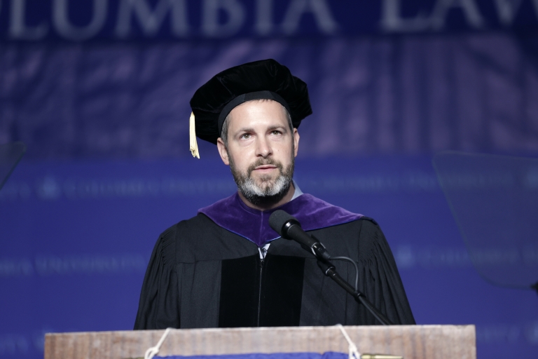 Professor in cap and gown at podium