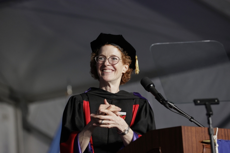 Woman with red hair and glasses in graduation gown and cap