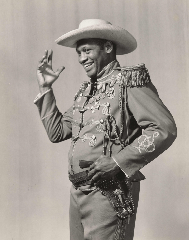  Paul Robeson in the stage production The Emperor Jones, smiling and gesturing toward his broad-brimmed hat.