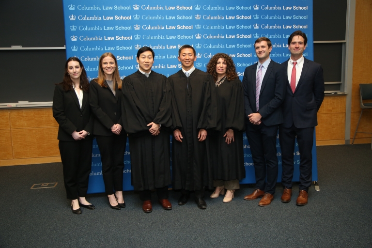 Seven people standing in front of a background that says Columbia Law School