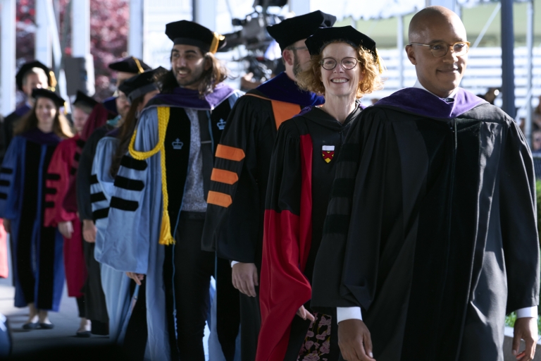 A line of faculty and students in academic regalia walking