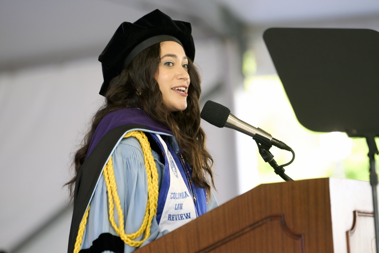 Woman in graduation regalia at podium