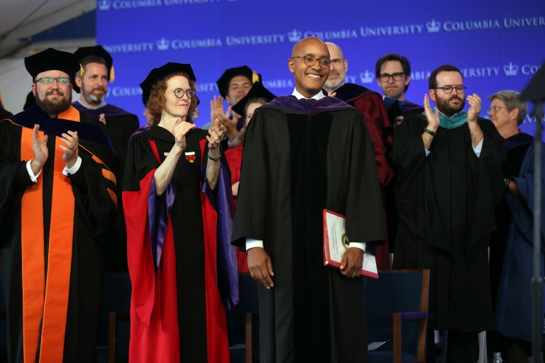 People in academic regalia applauding