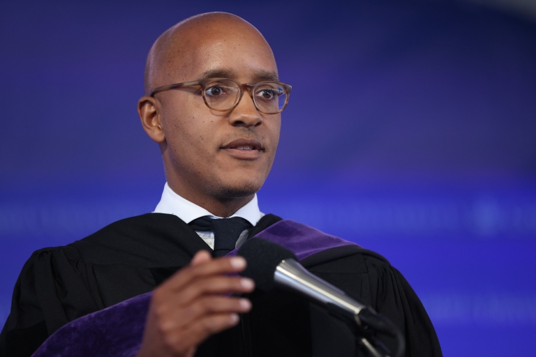 Man with glasses in academic gown at mike