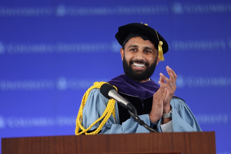 Bearded man in academic regalia at podium